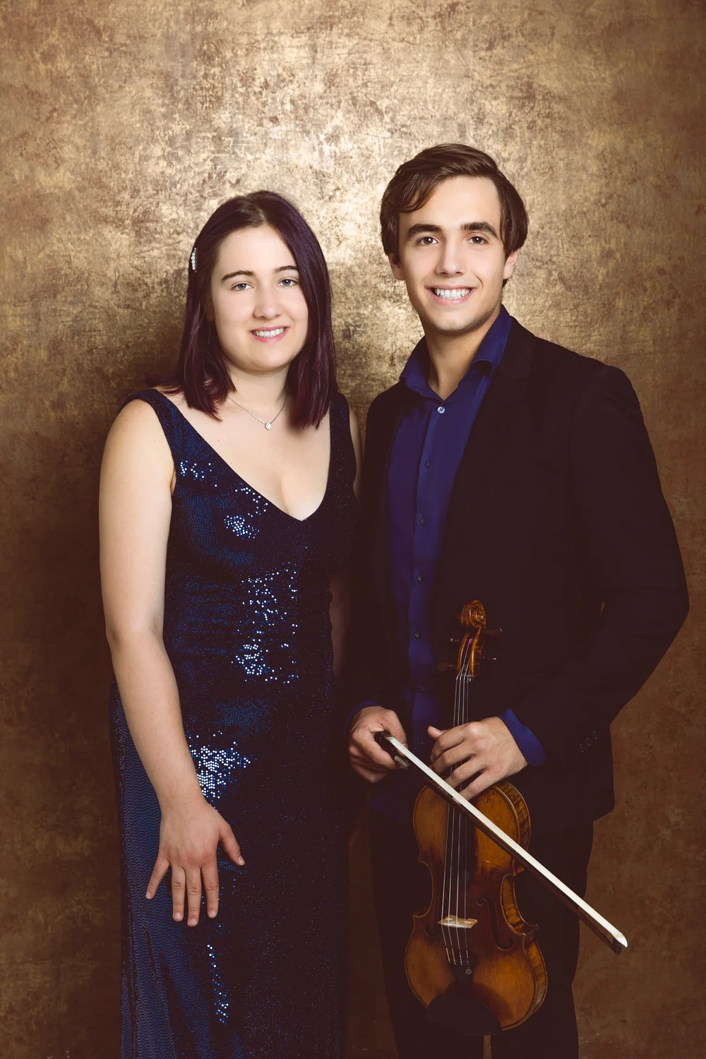 Pauline und Lewin Creuz mit Violine vor goldenem Studiohintergrund